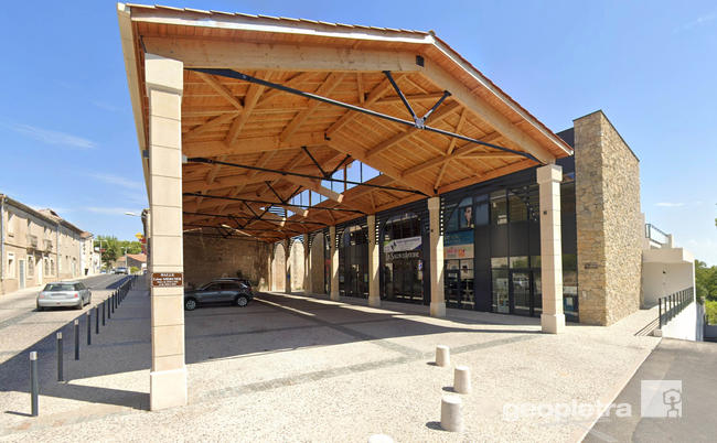 Commercial space near Montpellier with walls clad in manufactured stone Geopietra, in perfect harmony with the local native stone. Modern structure with a large wooden canopy.
